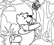 Coloriage Winnie ourson s'amuse avec le papillon entres les arbres