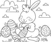 Coloriage Lapin de P&acirc;ques entour&eacute; par des oeufs et tenant une carotte